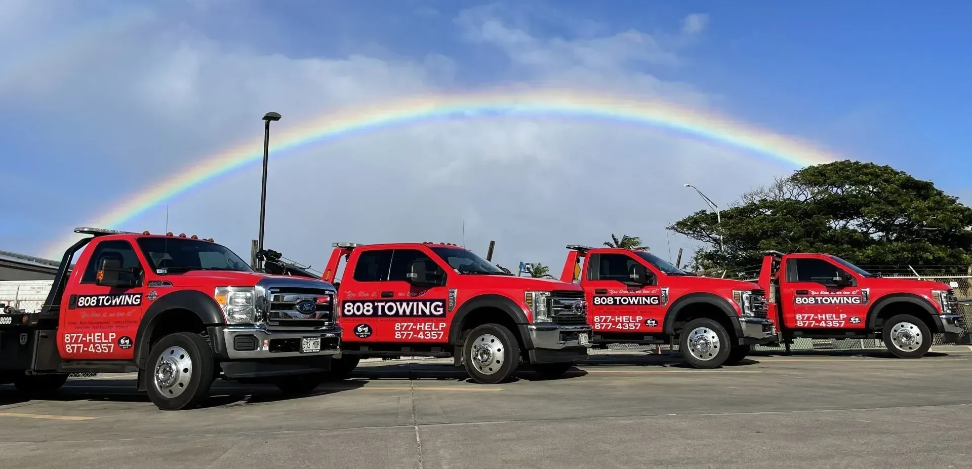 808 Towing's fleet of red trucks beneath a Maui rainbow