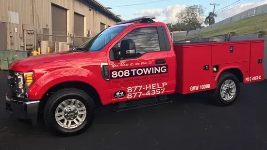 A red 808 Towing service truck parked in front of a building